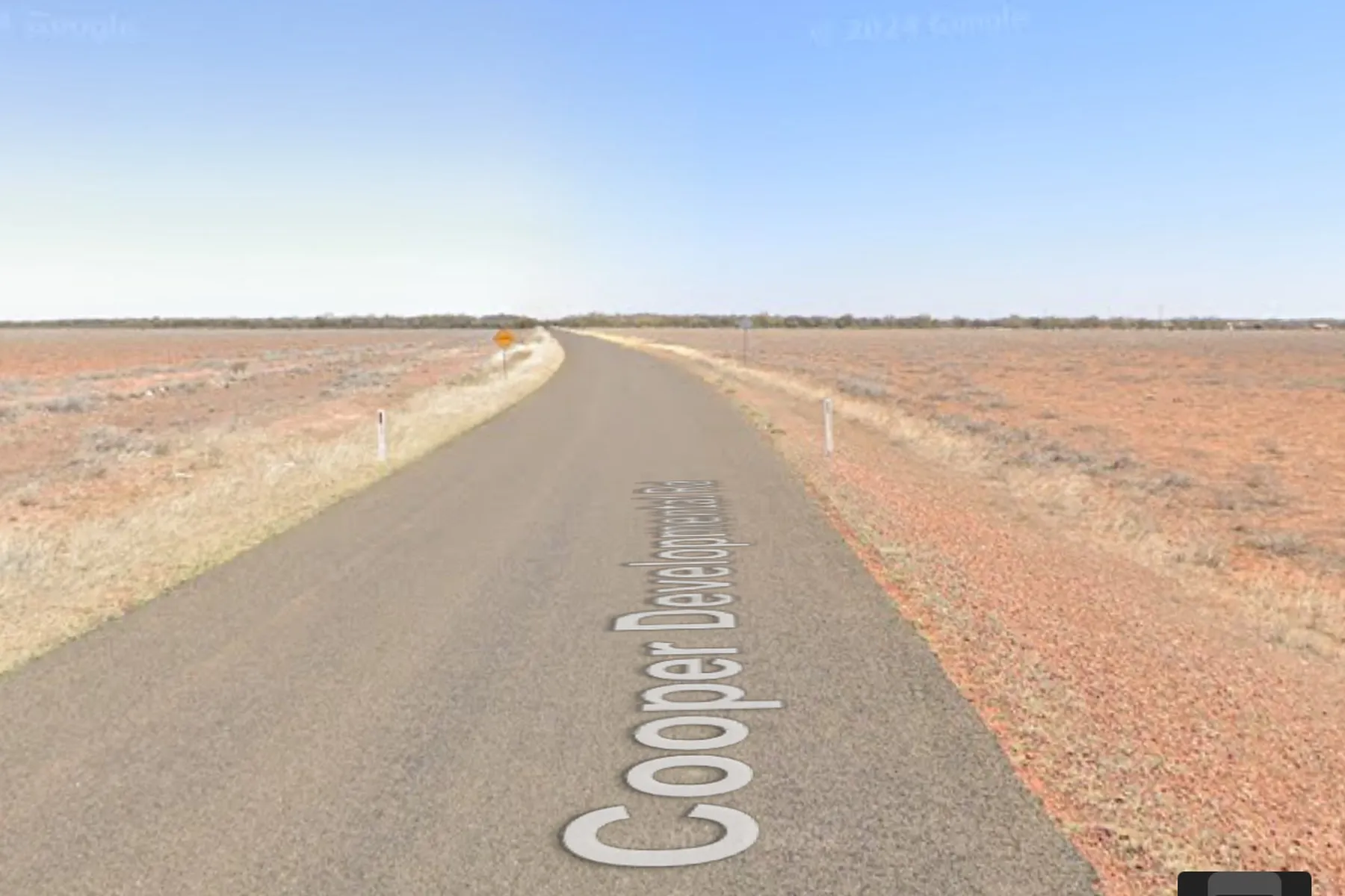 A straight outback road through red earth under a pale blue sky, as shown in a Latlas round.